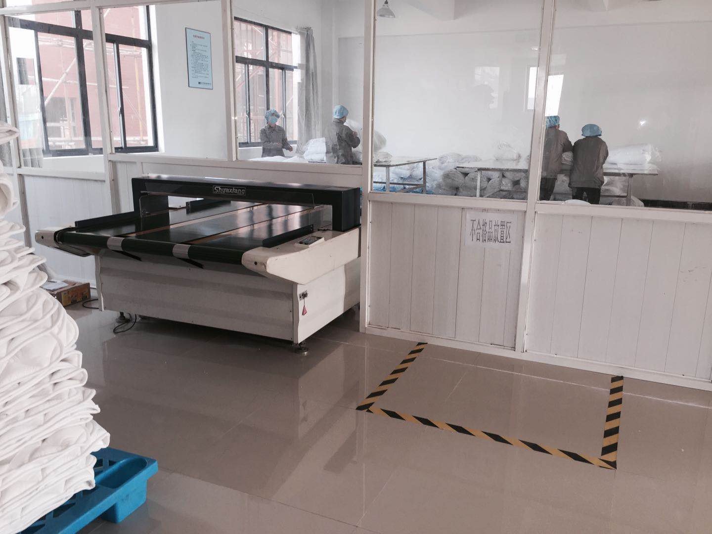 a metal testing machine, workers inspect the home textile products before packing