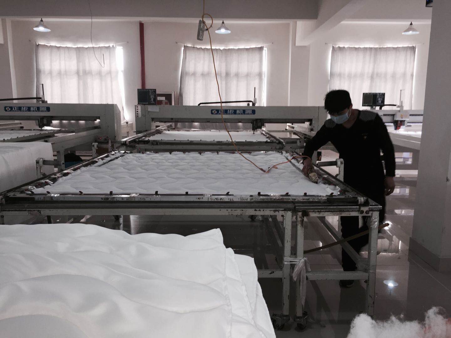 a worker is working besides the quilting machine